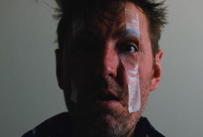 A man with a bandaged wound on his face