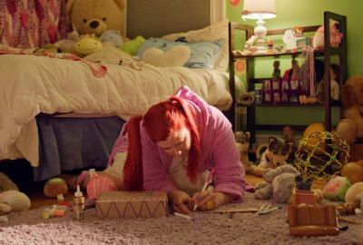 A young woman writes on paper in her bedroom