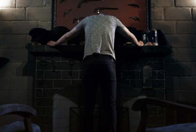 Apostles film still headless man leans against a table