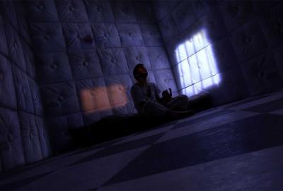 Asylum person sitting in a dark padded room