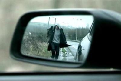 Detour man walking  image is seen in a cars sideview mirror