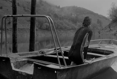 CODA SACRA film still woman on a boat in a calm lake.