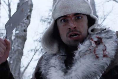 Ice Man film still bloodied man standing with a small shovel in his hand.