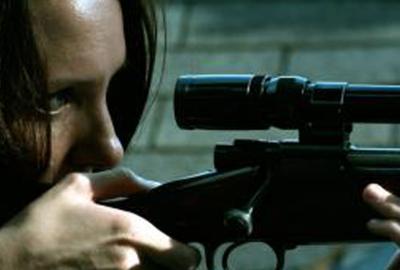 Leftovers woman looks through scope on rifle