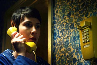 The Night Caller woman talks on a yellow landline phone