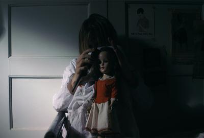 Trash Fire film still young woman sits in the dark with a creepy doll