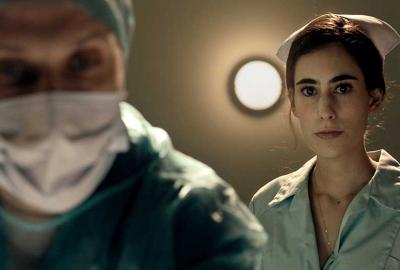 Surgery doctor looks down at patient with nurse behind him